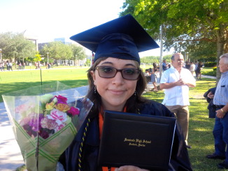 Lizzy holding up her high school diploma